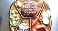 Tatár beefsteak készre keverve, vajjal és kerti javakkal tálalva 
